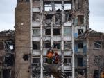 Dos trabajadores reparan las l&iacute;neas el&eacute;ctricas frente a edificios da&ntilde;ados en Mariupol, Ucrania.