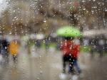 Varias personas se protegen de la lluvia con un paraguas este domingo en Pamplona.
