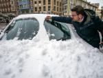 Un hombre quita la nieve de su coche en Burgos.