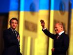Macron y Scholz saludan con la bandera de Ucrania proyectada de fondo.