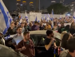 Con banderas y abucheos, cientos de manifestantes se re&uacute;nen frente a una peluquer&iacute;a en Tel Aviv.
