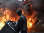 Un manifestante pasa por delante de las llamas en una protesta en Par&iacute;s.