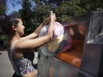 Una mujer recicla ropa en un contendor.