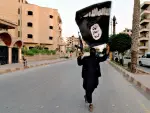 Persona levantando un arma y la bandera del Estado Islámico (archivo).