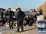 Varios migrantes esperan en la isla de Lampedusa.