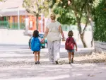 Una madre y sus dos hijas caminando al colegio.