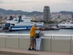 Una pareja conversa frente a la terminal de cruceros del Puerto de Barcelona.