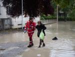 Miembo de la Cruz Roja ayuda a los vecinos a evacuar sus casas por las inundaciones en Italia.