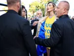 Alina Baikova trata de mostrar un mensaje contra Putin en la alfombra roja de Cannes, ante la oposici&oacute;n del equipo de seguridad.