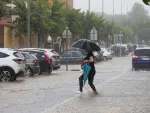 Una mujer cruza una calle inundada tras la tormenta de granizo y agua que ha caído en la pedanía de La Alberca (Murcia).