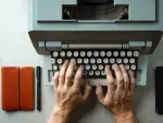 Una máquina de escribir, siendo utilizada por una persona