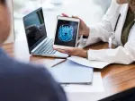 Unrecognizable female doctor shows a male patient an image of his brain from an MRI scan. The image is on a digital tablet.