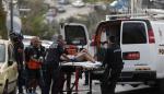 Un hombre en una camilla, sospechoso de ser el atacante, es llevado a una furgoneta por agentes de policía israelíes.