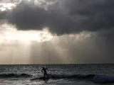La amenaza del Fay. Un surfista en una playa de La Habana, poco antes del paso de la tormenta tropical Fay, que ya ha causado tragedias en la zona del Caribe. En Haití han muerto 50 pasajeros de un bus en un accidente causado por las fuertes lluvias.