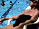 Una bañista toma el sol mientras otras dos se refrescan en la piscina municipal al aire libre del Canal de Isabel II de Madrid. Las altas temperaturas de los últimos días ha incrementado el número de visitantes en las distintas instalaciones municipales.