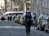 Un policía camina en una calle cercana a un juzgado de paz en Bruselas (Bélgica), donde una jueza y un funcionario han sido abatidos a tiros.