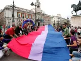 Representantes de la Federaci&oacute;n Estatal de Lesbianas, Gays, Transexuales y Bisexuales despliegan la 'bandera bisexual' m&aacute;s grande de Europa, este jueves en la Puerta del Sol de Madrid.