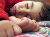 Un niño pequeño durmiendo sobre la cama.