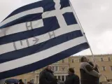 Un manifestante sostiene una bandera de Grecia frente al Parlamento griego en Atenas.