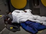 Dos personas sin hogar duermen en un cajero automático en Barcelona.
