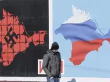Un viandante pasa por delante de un cartel que anima a la poblaci&oacute;n a votar en el refer&eacute;ndum sobre Crimea, en Sebastopol (Ucrania).