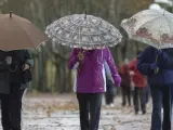 Tres mujeres pasean por Valladolid protegiéndose con paraguas del aire y la lluvia.