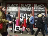 Varias personas pasean ante un escaparate donde se anuncian las rebajas del Black Friday, en Oxford Street, Reino Unido. La policía británica recibió esta madrugada más de una decena de llamadas de supermercados ante la avalancha de personas que se aglutinaron para conseguir las mejores ofertas.
