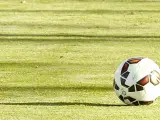 Un balón se desplaza sobre el césped durante un encuentro de fútbol.