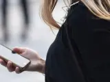 Una mujer usa su 'smartphone' mientras pasea por la calle.