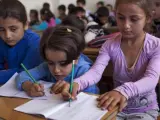 Niños sirios durante una clase de primaria en un colegio del distrito de Saif Al-Dawla, en Alepo (Siria). El Fondo de las Naciones Unidas para la Infancia (Unicef) ha instado a aumentar los esfuerzos para que la ayuda humanitaria llegue a los cientos de miles de niños atrapados por el conflicto.