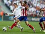Fabio Coentrao (L) del Real Madrid lucha por el bal&oacute;n con Raul Garcia (C) y Tiago Mendes del Atl&eacute;tico Madrid durante la UEFA Champions League 2014 en Lisboa.
