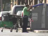 Un hombre rebusca en un contenedor de basura de Sevilla.