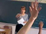 Alumnos de Secundaria levantan la mano en clase.