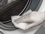 Una persona limpiando el moho de una lavadora.