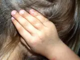 Una niña, tapándose los oídos.