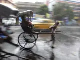 Un hombre corre con su "rickshaw" bajo la lluvia en Calcuta (India). La temporada de lluvias del monzón se da de junio a octubre.