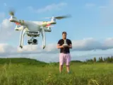Un hombre controla un dron en campo abierto.