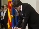 El presidente de la Generalitat, Carles Puigdemont, firma el documento sobre la Independencia despu&eacute;s de comparecer ante el pleno del Parlament para trasladar los resultados de la jornada del 1-O,