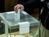 Un votante deposita un voto en una urna.