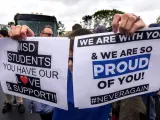Estudiantes del instituto Marjory Stoneman Douglas reparten carteles mientras esperan al autobús en Parkland, Florida.