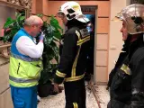 Un miembro del SUMMA y varios bomberos, en la puerta de la vivienda en la que dos menores fueron encontrados muertos tras un incendio ocurrido en la calle Benjam&iacute;n Palencia, en Getafe.