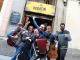 Los integrantes del grupo catal&aacute;n La Pegatina posan junto al que fue su bar durante tres d&iacute;as en Madrid