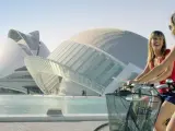 Dos turistas pasan en bicicleta junto a la Ciudad de las Artes y las Ciencias de Valencia.