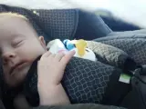 Un bebé duerme en la silla infantil de un coche.