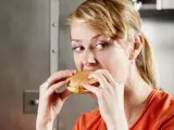 Una mujer se come una hamburguesa.