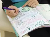 Una estudiante de instituto garabateando en su cuaderno.