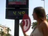 Una joven se abanica ante un termómetro que marca 44ºC debido a la ola de calor.