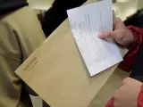 Una persona porta un sobre del voto por correo para las elecciones del 28-A mientras espera su turno en una oficina de Correos.