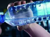 Un hombre bebe agua de una botella de plástico.