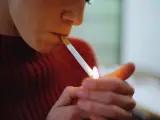 Una mujer enciende un cigarrillo.